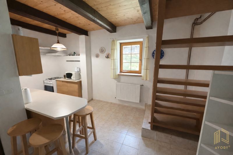 A kitchen in a family house with wooden decor, open stairs, and tables.