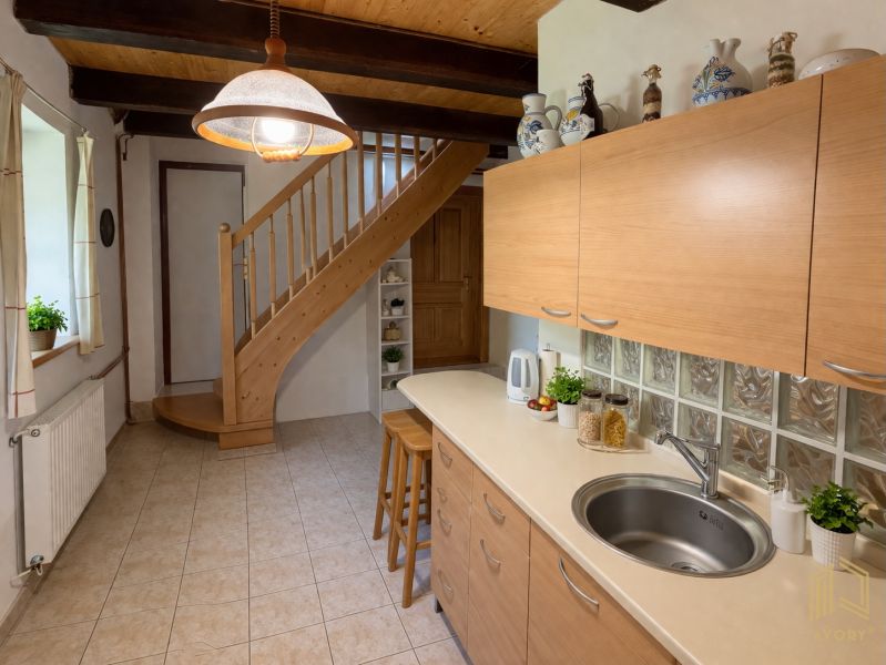 A family house with a kitchen, staircase, bar stools, and a wooden-patterned floor.