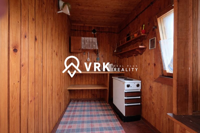 Wooden walls, stove, and shelves in an interior with a wood-patterned floor.