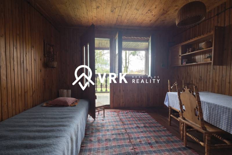 Interior of a cabin with wooden decor, bed, table, chairs, and a small rug.