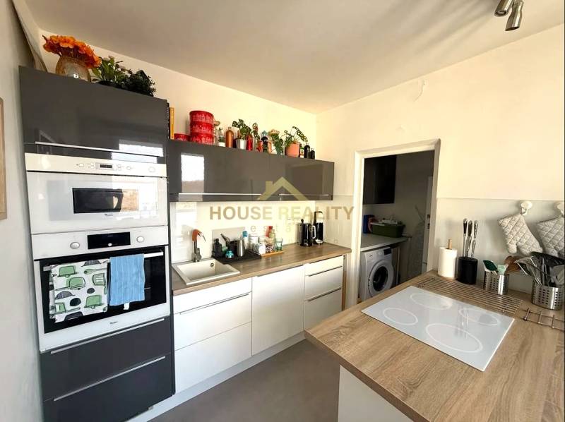 A kitchen in a 3-room apartment with a wooden decor floor, built-in appliances, and decorations.