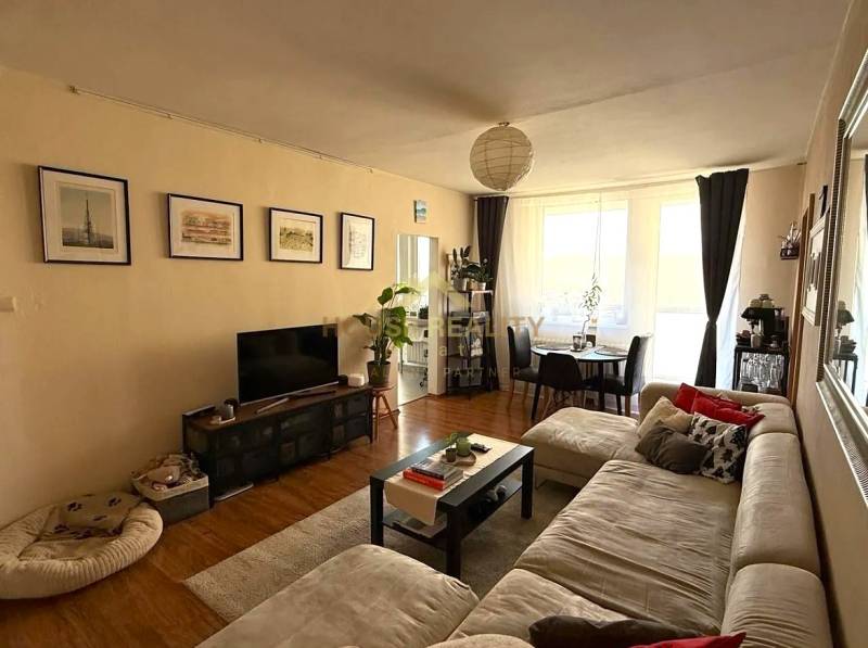 Living room of a 3-room apartment with a sofa, television, and dining table, floor with wooden decor.