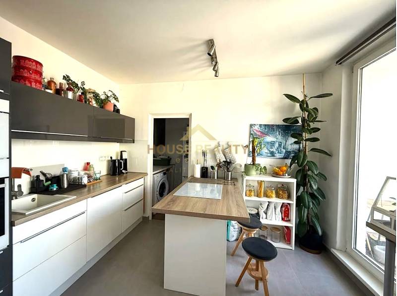 A kitchen with appliances and a wooden decor floor in a 3-room apartment.