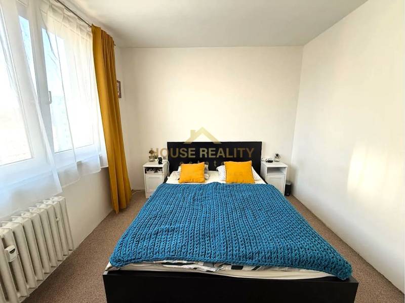 A bedroom with a bed, yellow pillows, and a blue blanket in a 3-room apartment.