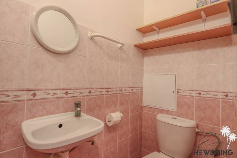 A bathroom with pink tiles and sanitary ware in a 2-room apartment.