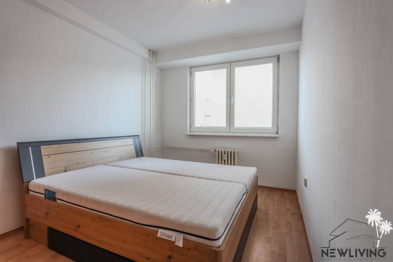 Bedroom with a bed and wooden decor flooring in a 2-room apartment.