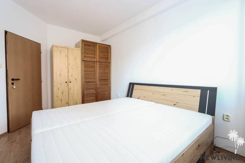 A bedroom in a 2-room apartment with a bed and wooden wardrobes, flooring with a wooden decor.