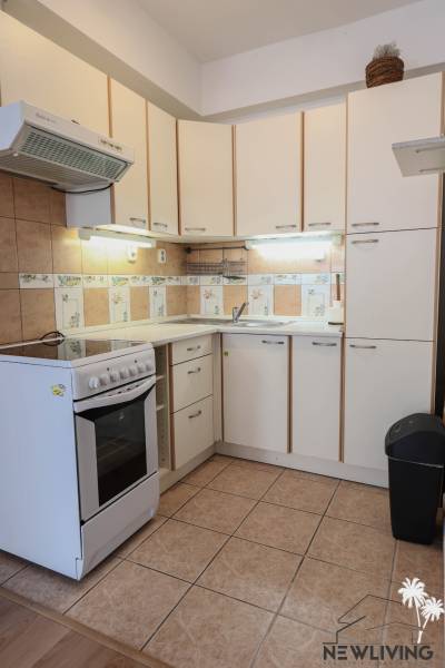 Kitchen in a 2-room apartment with white cabinets and a stove, floor with wood decor.