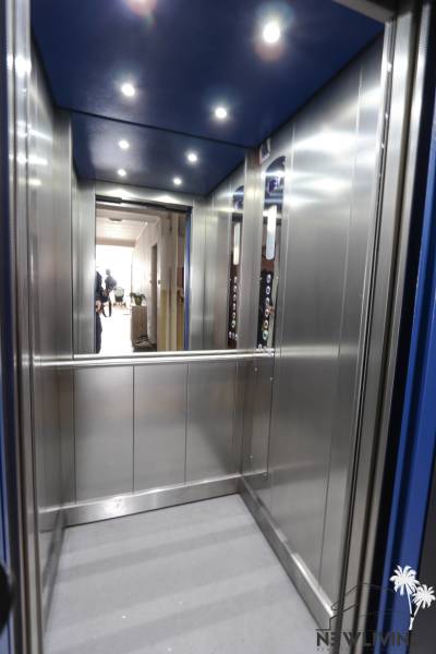 Interior of an elevator with lighting and metal walls in a 2-room apartment.