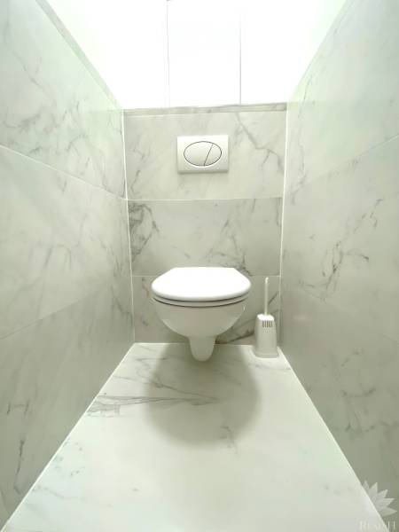 Bathroom with wall-hung toilet and marble tiles in a 2-room apartment.