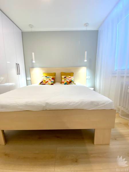 Bright bedroom in a two-room apartment with colorful pillows on the bed.