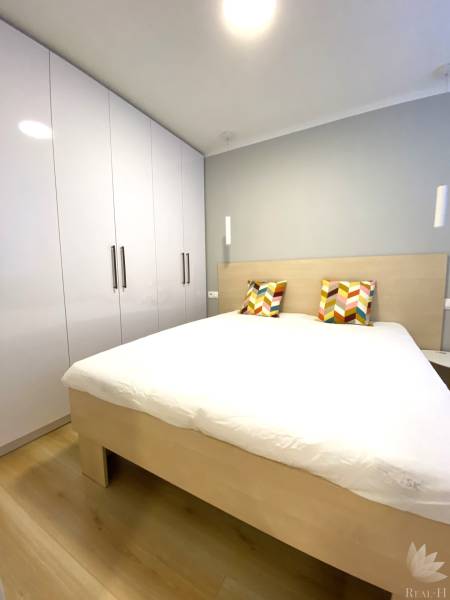 Bedroom with a double bed, colorful pillows, and a wardrobe, 2-room apartment.