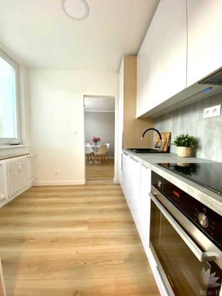 A kitchen in a 2-room apartment with white cabinets and a wood-patterned floor.