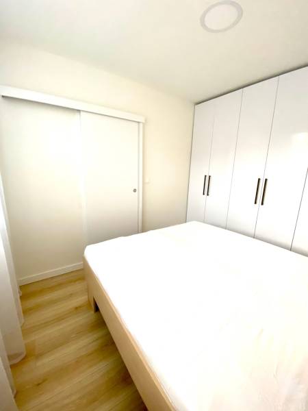 Bedroom in a 2-room apartment with a bed and a large built-in wardrobe.