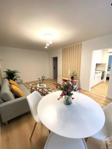 Dining room in a 2-room apartment with a white table and a wooden decor floor.
