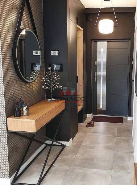 Entrance hall with a round mirror, wooden console, and decorative elements in a family house.