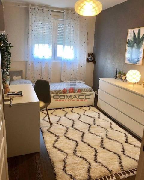 Children's room with a desk, carpet, and wooden decor flooring in a family house.