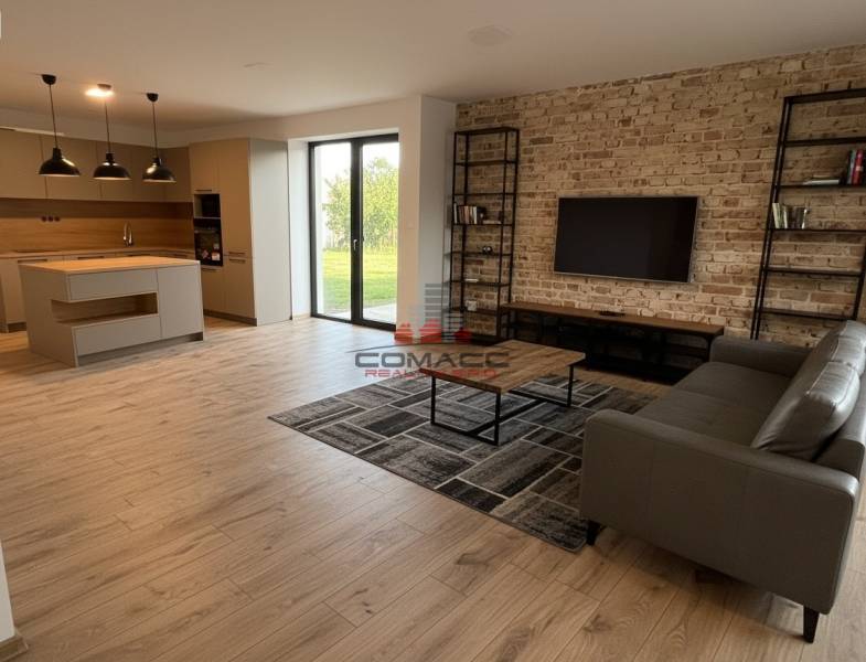 Living room with kitchen in a family house with a wooden decor floor and a brick wall.