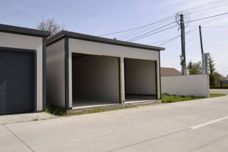 Garages in Michal na Ostrove with two open entrances, next to the road and the fence.