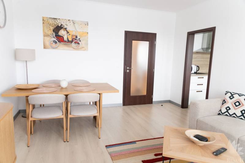 Dining room in a 4-room apartment with a wooden decor floor and an artistic painting on the wall.