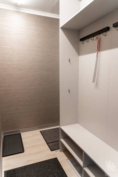 Entrance hallway with light-colored walls, wood-patterned flooring, cabinets, storage spaces.