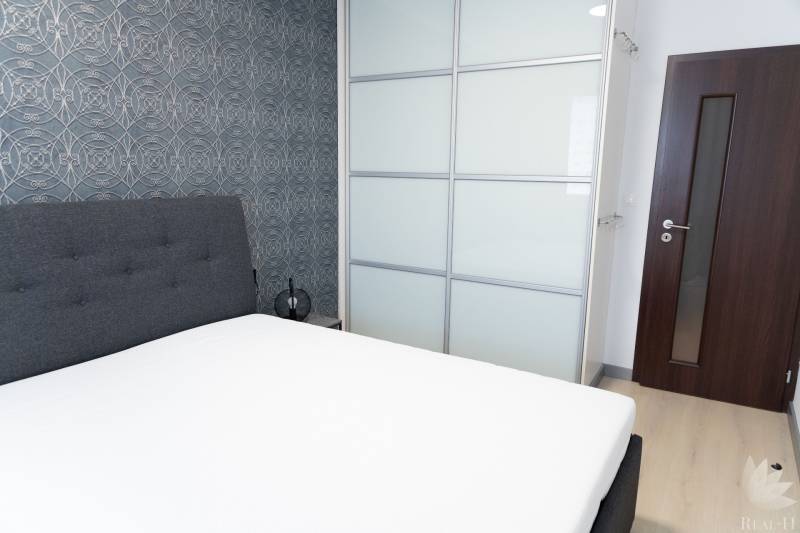 Bedroom in a 4-room apartment with an upholstered bed, wallpaper, and a built-in wardrobe.