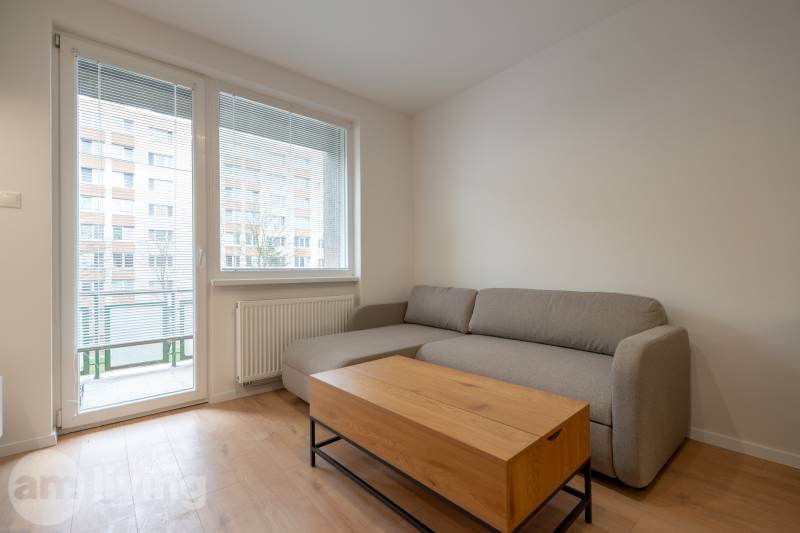 A gray sofa in a 3-room apartment with a table and a wooden decor floor.