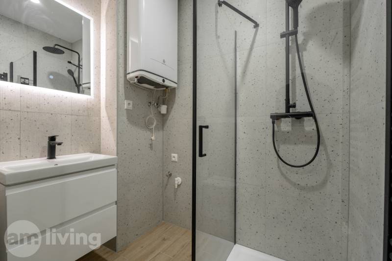 A bathroom with a shower and a floor with a wooden decor in a 3-room apartment.