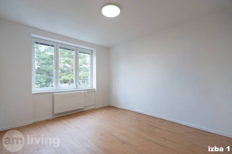A spacious room with a large window and a wooden decor floor in a 3-room apartment.