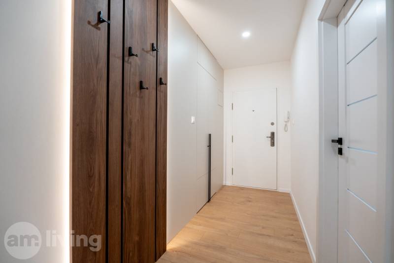 A narrow hallway with built-in cabinets and a wooden-patterned floor in a 3-room apartment.