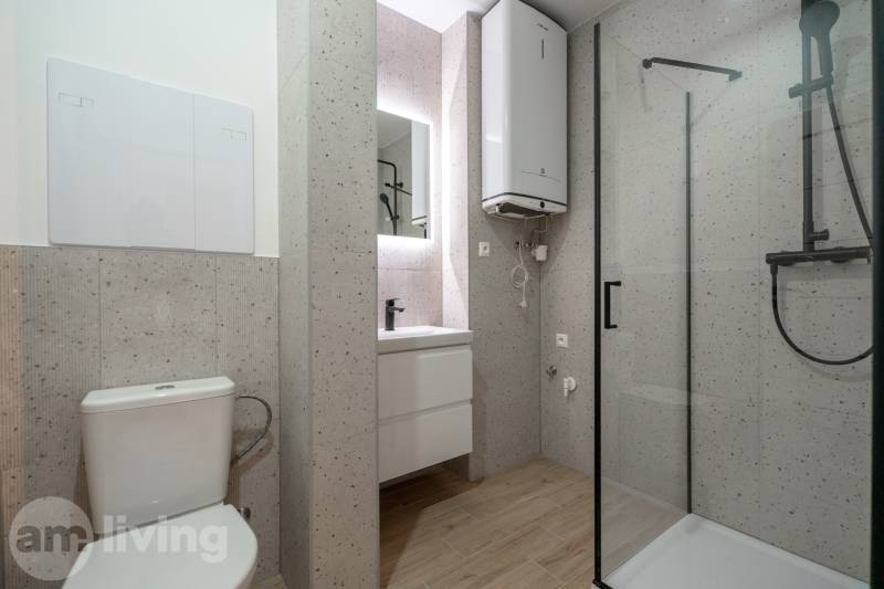 A bathroom in a 3-room apartment with a wooden decor floor and a shower corner.