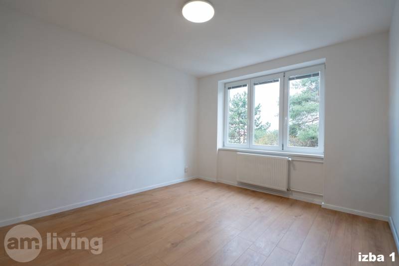 A spacious room with a large window and a wooden decor floor in a 3-room apartment.