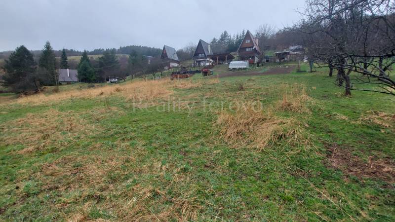 Extensive recreational plots in Púchov with cottages and greenery lined with trees.