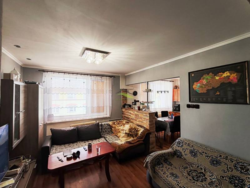 Living room with a sofa set, wooden decor flooring, and a light chandelier in a 4-room apartment.