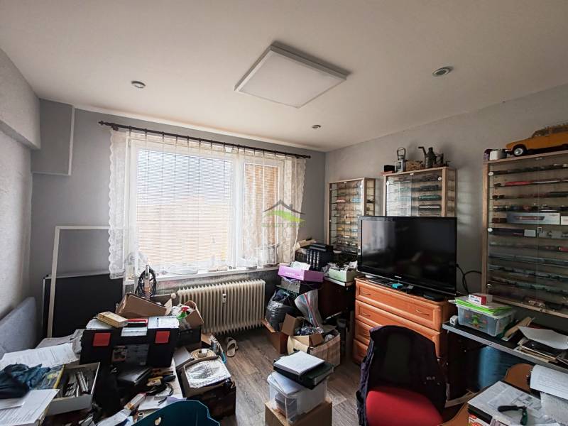 A room in a 4-room apartment with a wood-patterned floor and plenty of storage boxes.