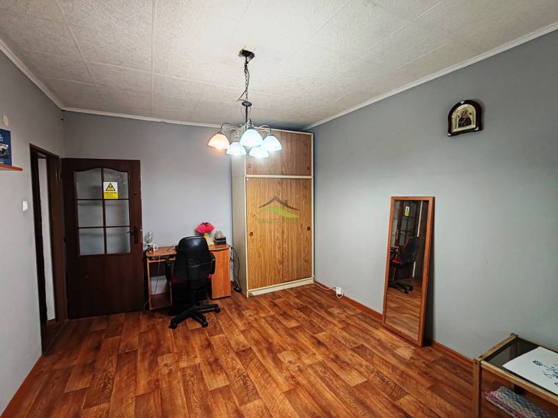 A room in a 4-room apartment with a wooden decor floor and a desk.