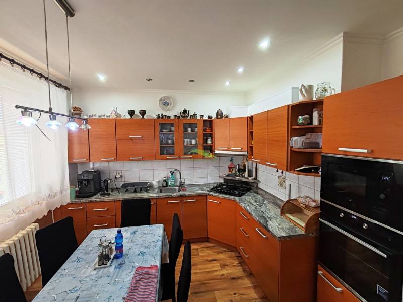 A kitchen unit with a wooden decor, a gas stove, and a dining table, in a 4-room apartment.