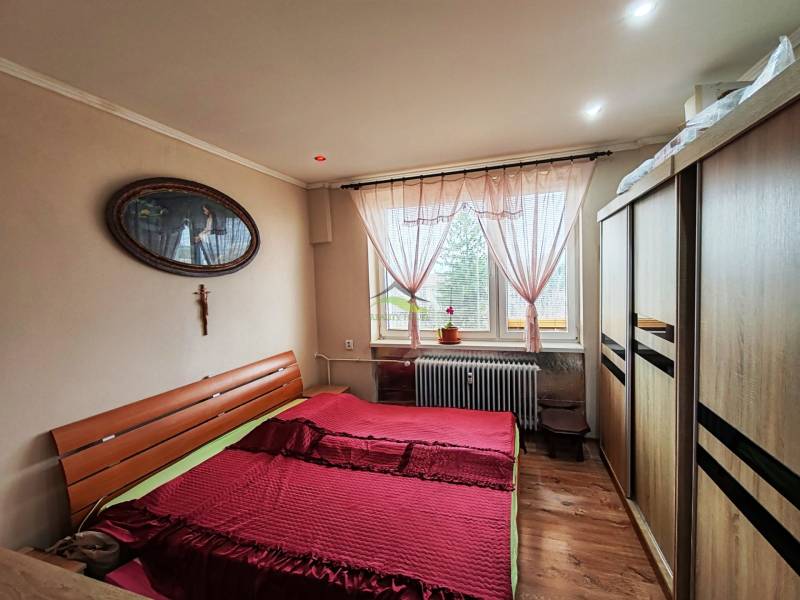 Bedroom in a 4-room apartment with a bed, wardrobe, and wooden decor flooring.