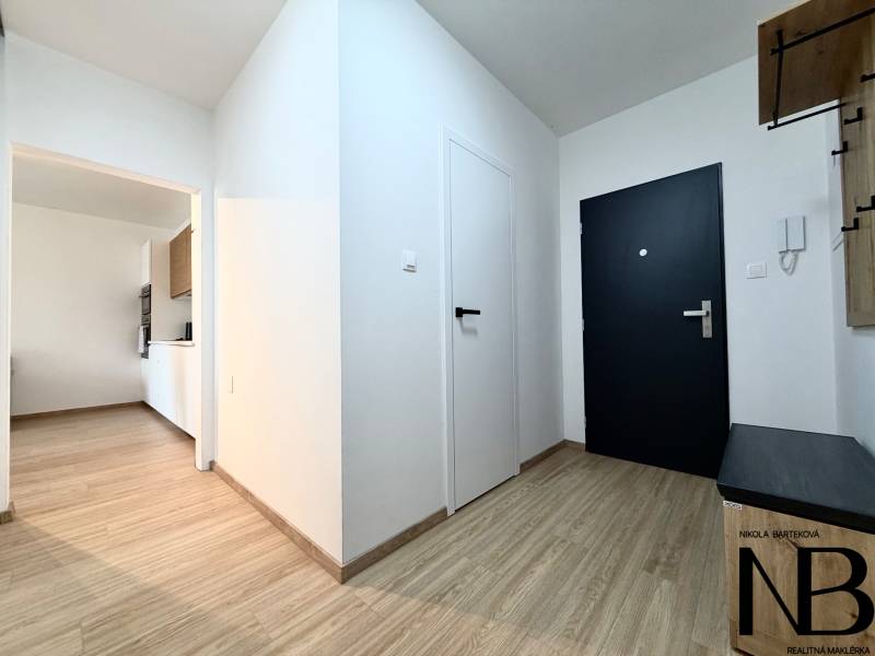 Interior of a 1-room apartment with wood-patterned flooring and white walls.