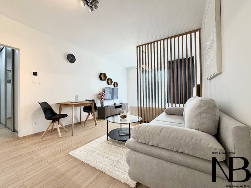 Stylish 1-room apartment with wood-patterned flooring, a sofa, and a dining area.
