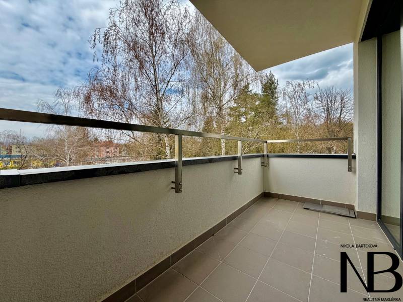 The balcony of a one-room apartment on Soblahovská Street in Trenčín with a view of the trees.