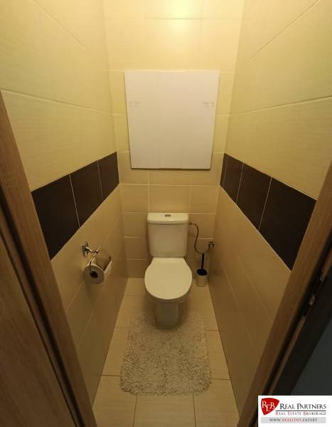 Bathroom in a 4-room apartment with a toilet and tiles, complemented by a light carpet.