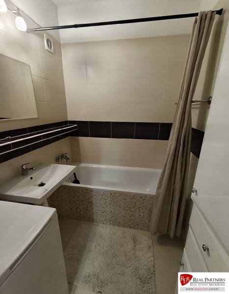 A bathroom with a shower curtain, bathtub, and sink in a 4-room apartment.