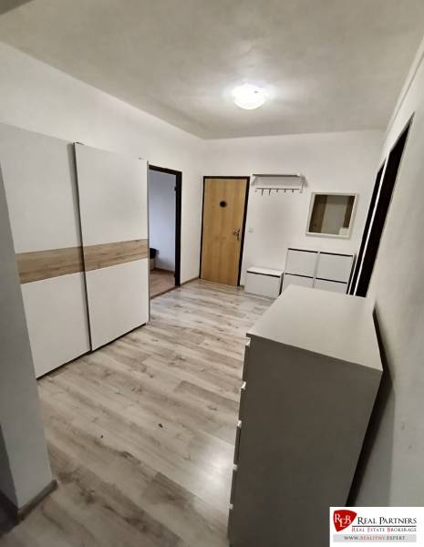 A hallway with white furniture and a wooden decor floor in a 4-room apartment.