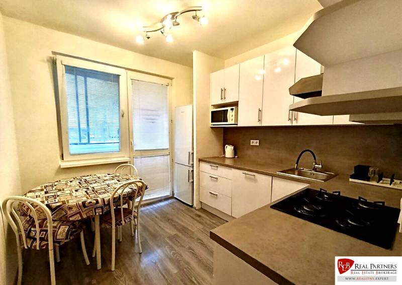 A kitchen in a 4-room apartment with a wood-patterned floor, white cabinets, and a dining area.