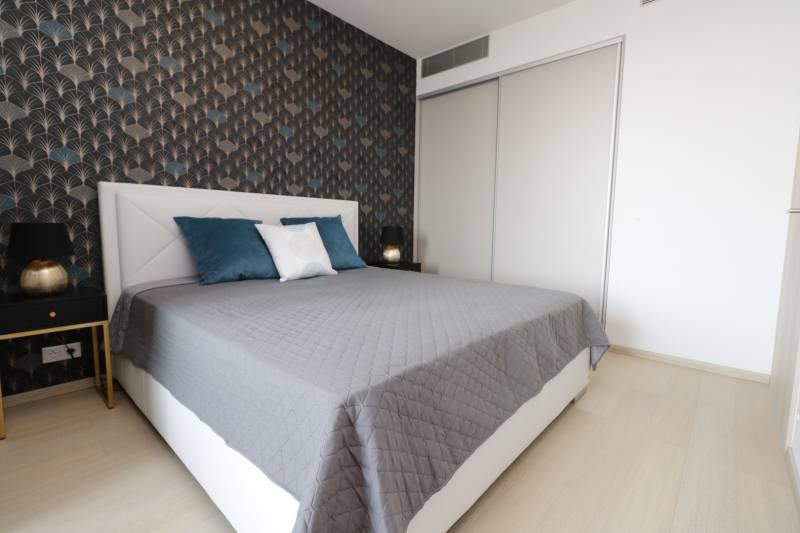Bedroom with a bed, patterned wall, wooden decor flooring, 2-room apartment.
