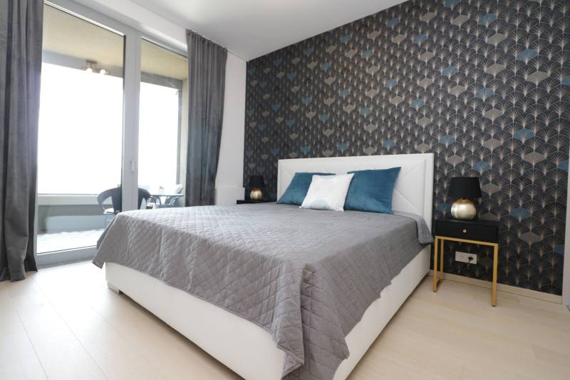 Bedroom with a bed, wallpaper, and access to a balcony in a 2-room apartment.