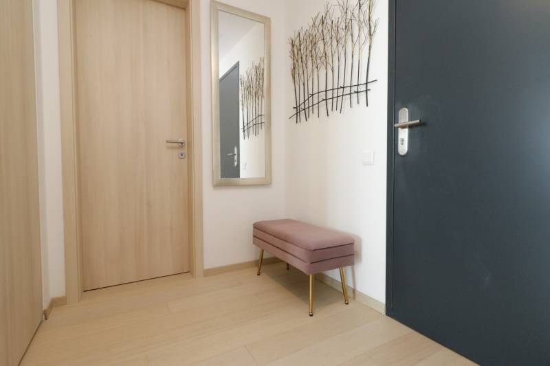 The entrance hall in a 2-room apartment with a wooden decor floor and a bench.
