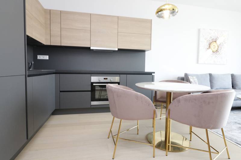 A kitchen in a 2-room apartment with a wood-patterned floor and a stylish table.