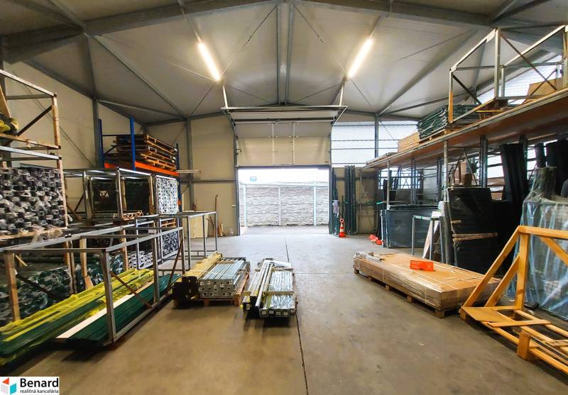 Commercial premises with stored material and an open gate, the floor has a concrete surface.